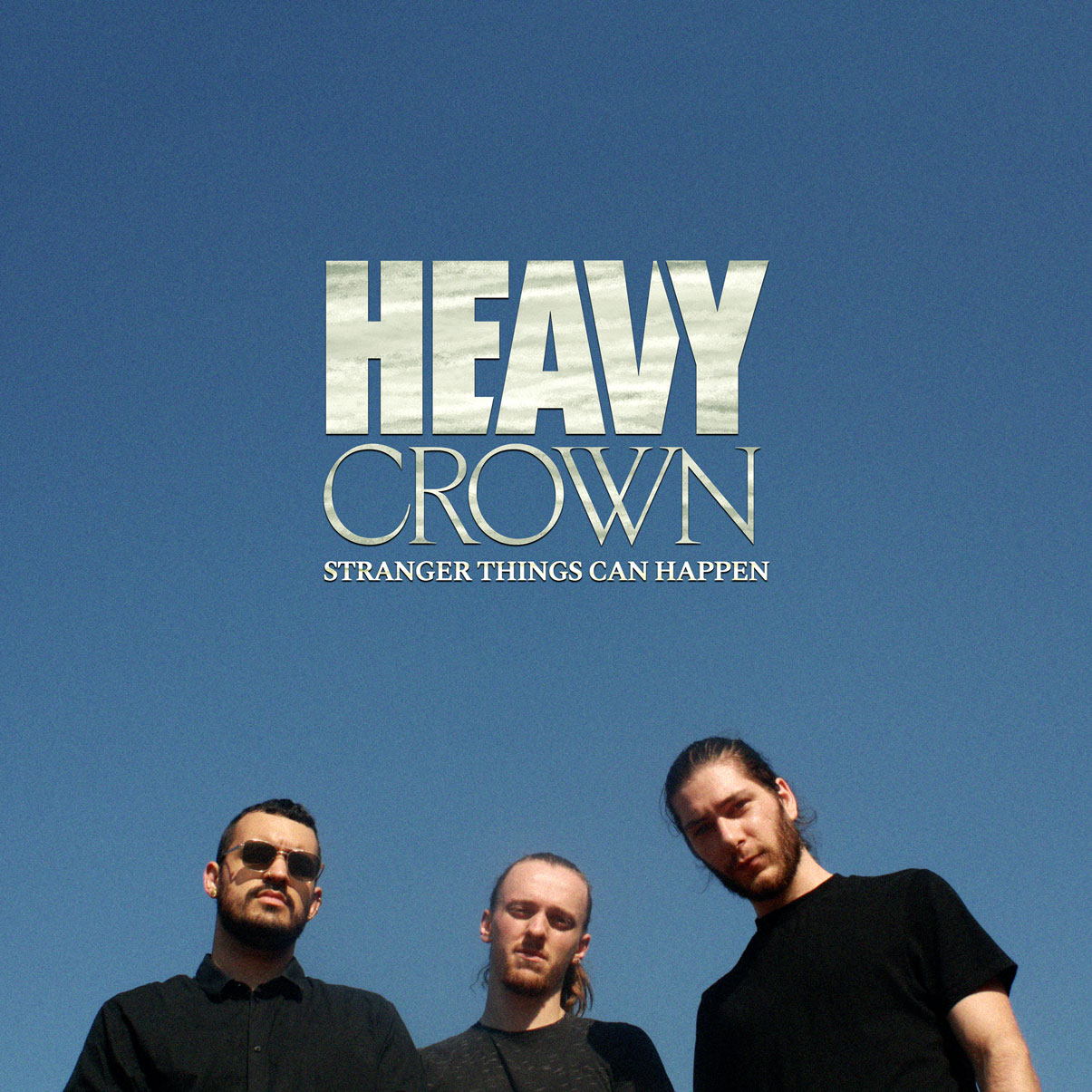 La pochette de l'EP de Heavy Crown, Stranger Things Can Happen. On y voit les 3 membres en bas de l'image sur un fond de ciel bleu. Le nom du groupe et de l'album sont affichés au-dessus de leur tête.